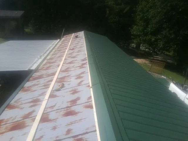 Old rusted panels beside newly installed green metal roofing — Wind Damage Roof Repair by Roofing Brothers in Port Monmouth