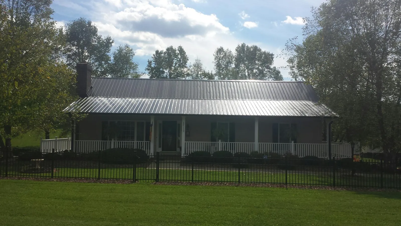 Gray metal roof on a brick ranch with a full width front porch — Gutter Guard Installation work by our crew in Port Monmouth