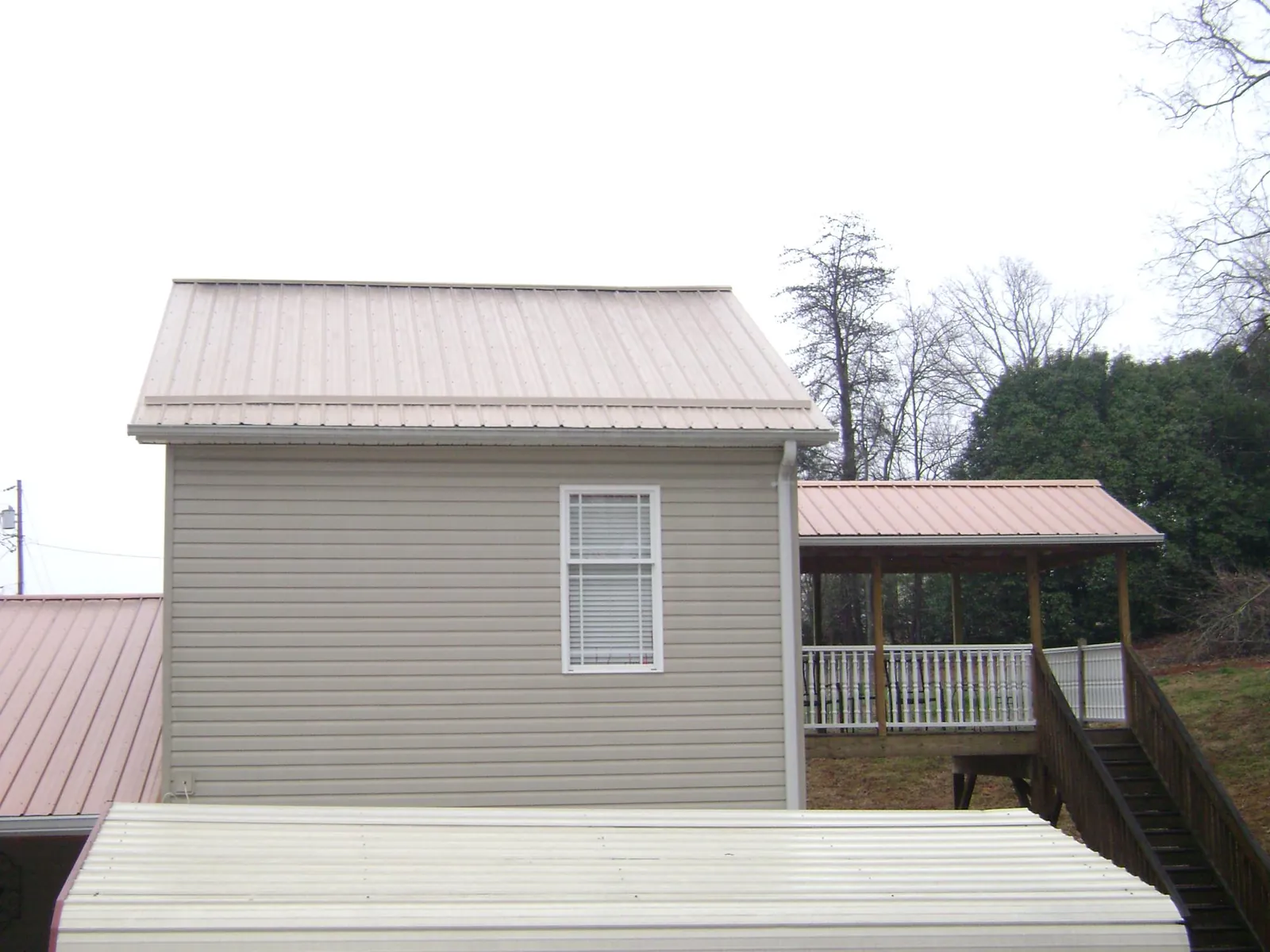 Tan metal roofs on a two story addition and attached porch, from a Roof Replacement job in Port Monmouth