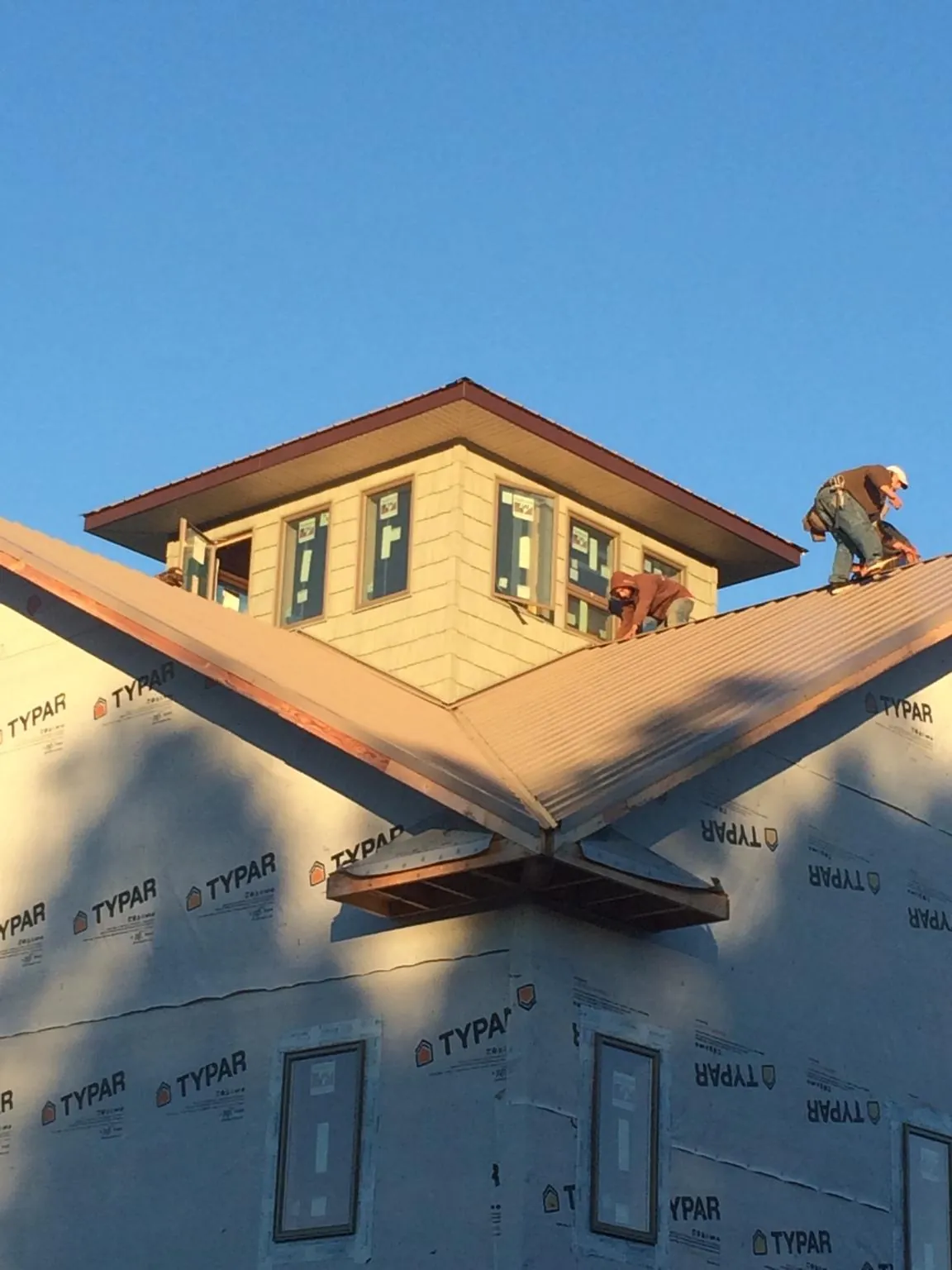 Roofers working around a rooftop cupola on a new metal roof at sunset — Roof Waterproofing in Port Monmouth by Roofing Brothers